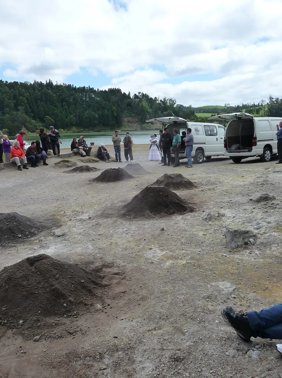 Os montes de terra que cobrem as panelas do cozido nas caldeiras da Lagoa das Furnas, com pessoas e carrinhas atrás.