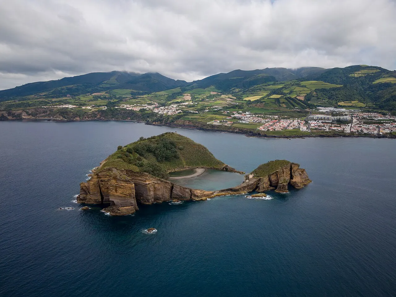 O Ilhéu de Vila Franca visto do alto, com a lagoa circular no centro da cratera e a vila na costa atrás.