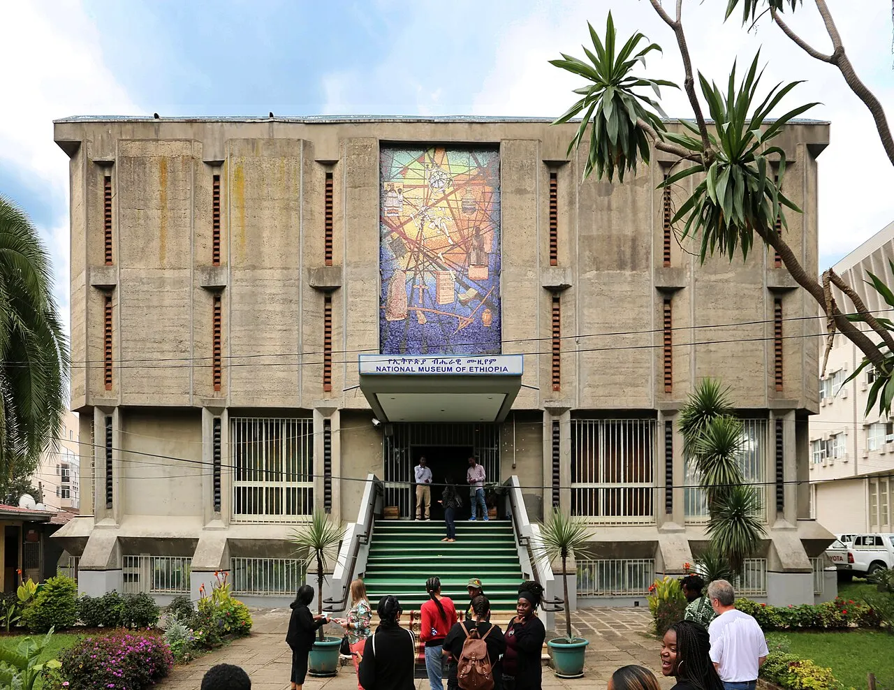 Fachada do Museu Nacional da Etiópia, em Adis Abeba, com painel colorido sobre a entrada e escadaria à frente.