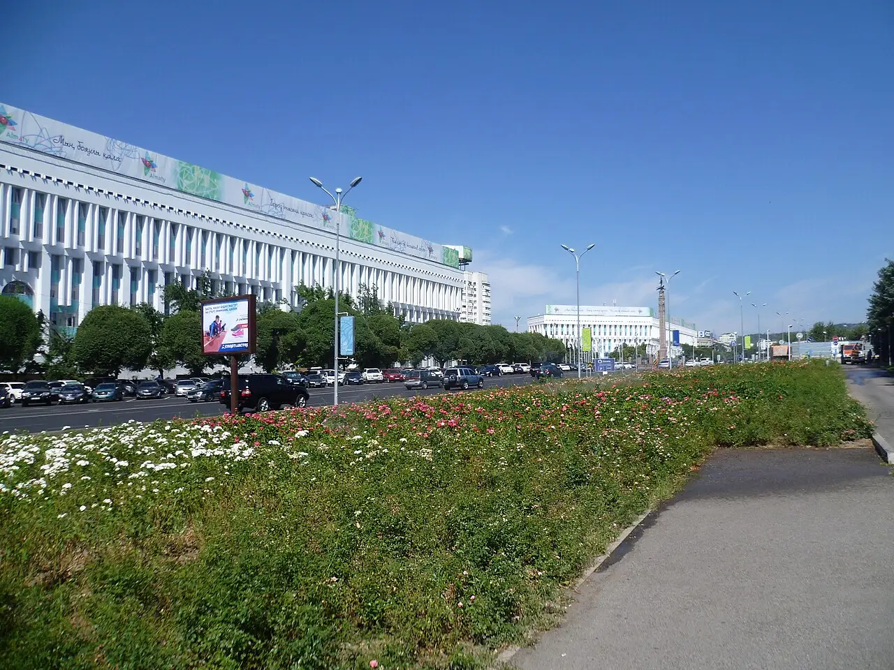 Prédio branco de colunas da Praça da República, com canteiro de flores e carros na avenida.