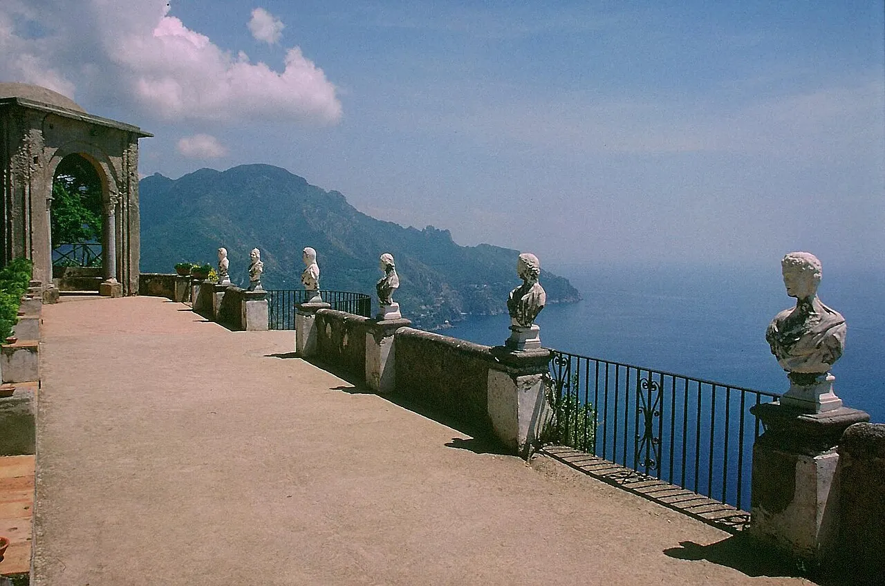 O Terraço do Infinito da Villa Cimbrone, em Ravello, com bustos de mármore sobre a balaustrada e a costa e o mar azul abaixo.