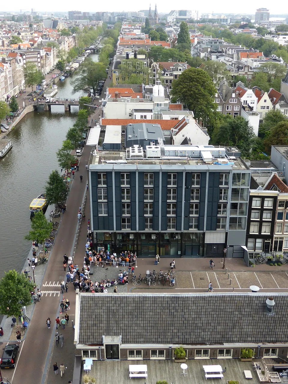 Casa de Anne Frank e o prédio do museu ao lado, à beira do canal em Amsterdã, vistos do alto.