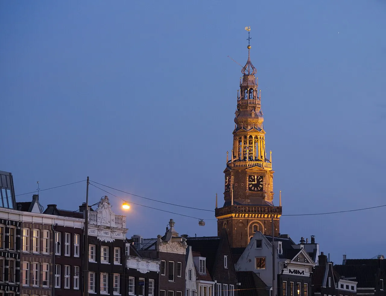 Torre da Oude Kerk, em Amsterdã, com a agulha e o carrilhão, contra o céu do fim de tarde.