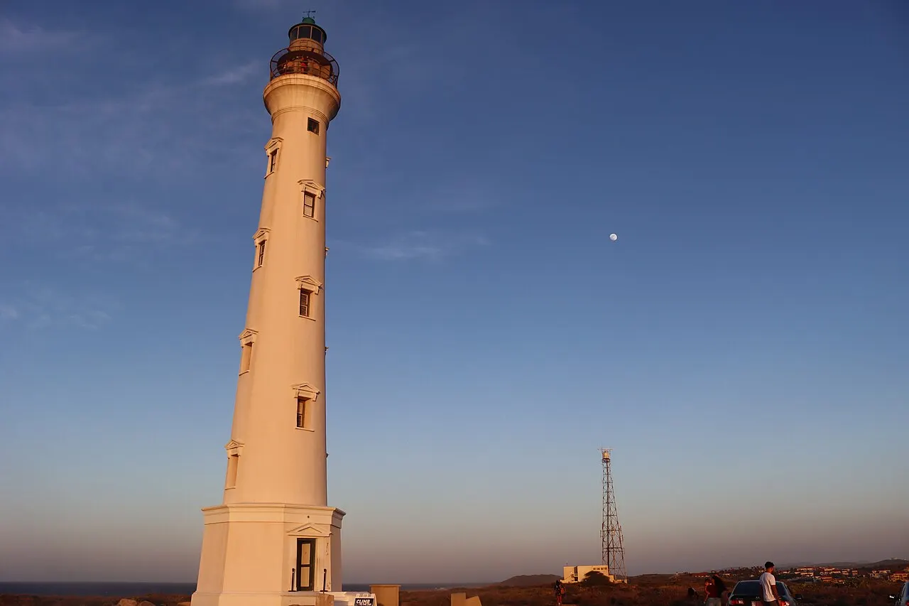 El Faro California, una torre alta de piedra clara con la linterna arriba, contra el cielo del atardecer.