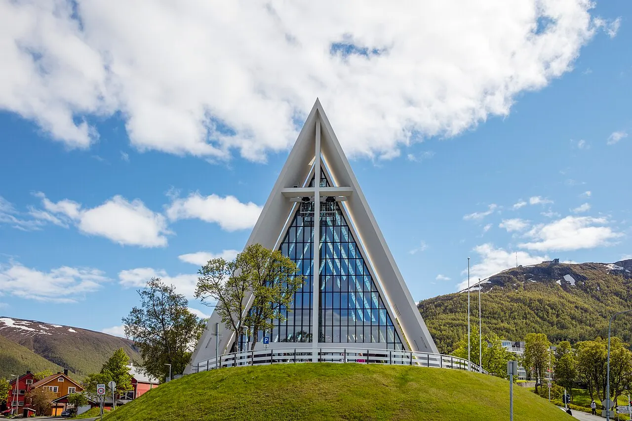 Catedral do Ártico, em Tromsø, com a fachada triangular de vidro e concreto sob céu com nuvens.