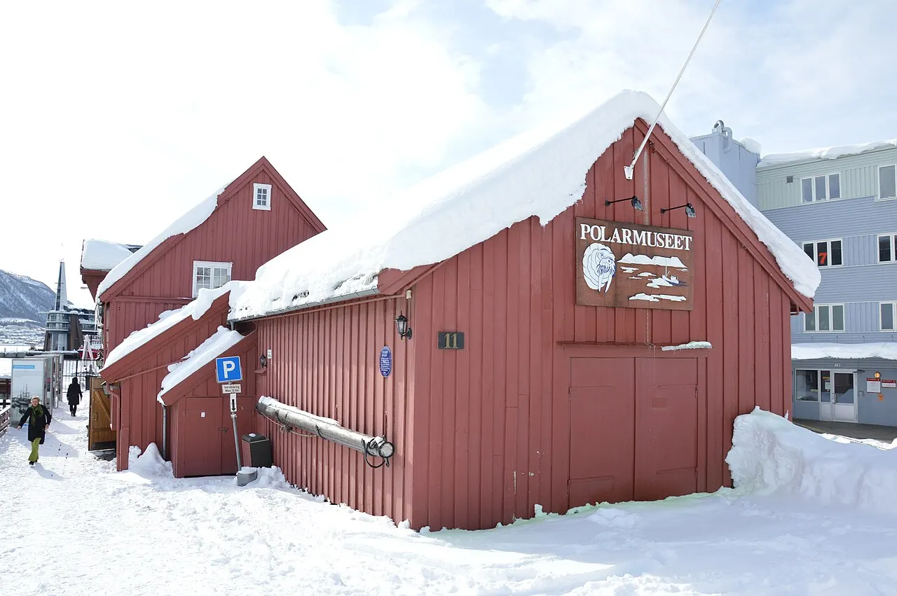Museu Polar de Tromsø, num antigo armazém de madeira vermelha com neve no telhado.