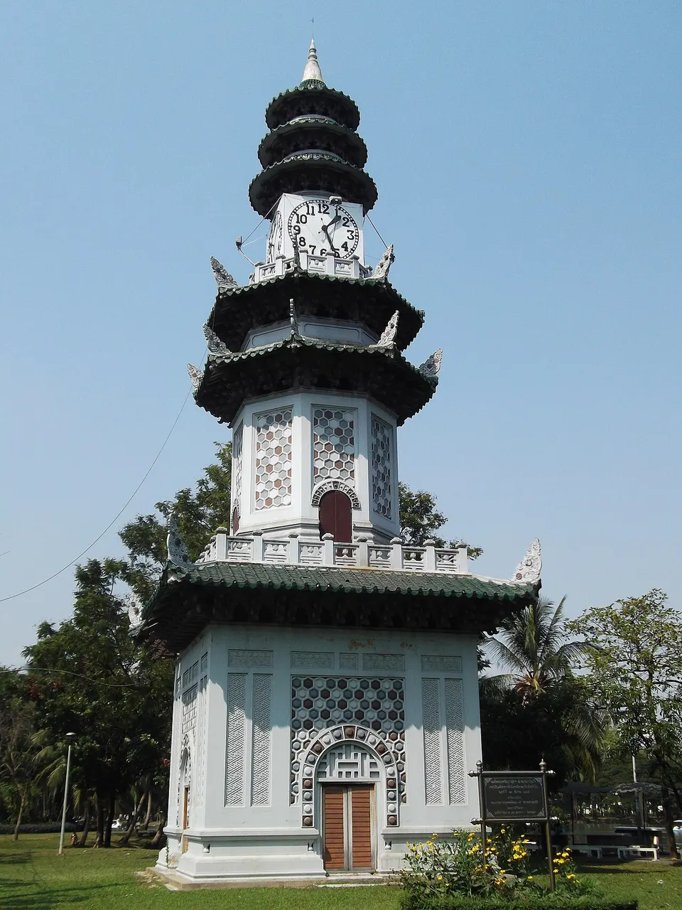 Torre branca de vários andares com telhados escuros escalonados e um relógio no corpo.