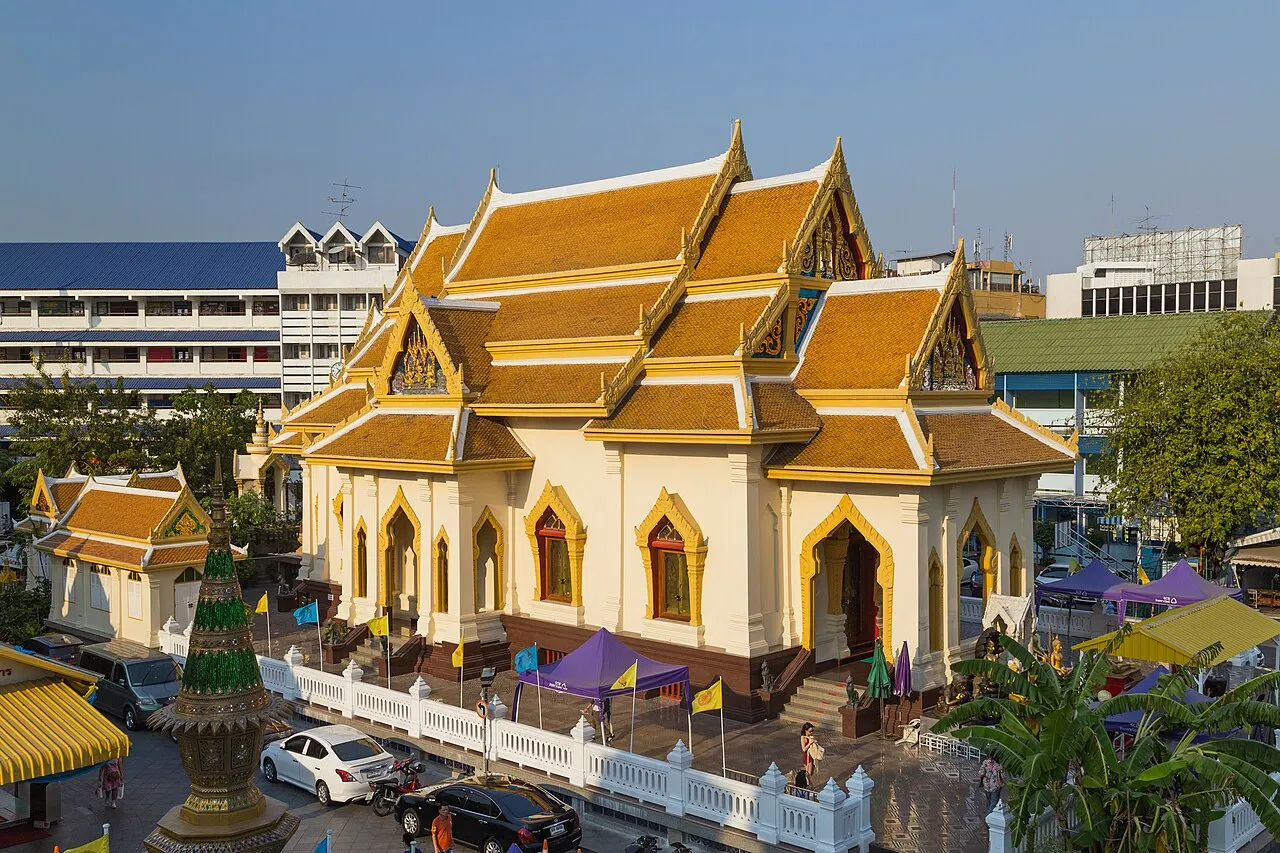 O Wat Traimit, templo branco e dourado com telhados tailandeses de várias águas e torres nos cantos.