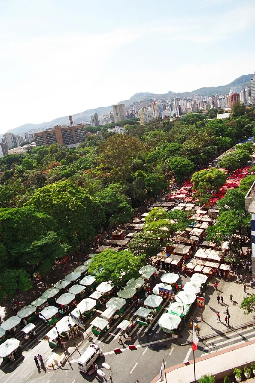 As fileiras de barracas da Feira Hippie na Avenida Afonso Pena, vistas do alto, ao lado das árvores do parque.
