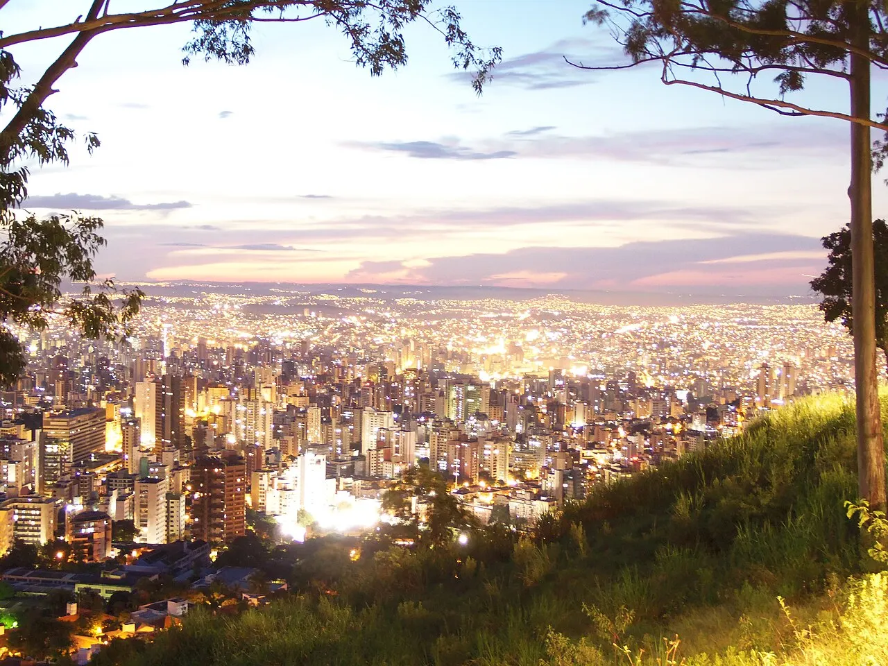 Belo Horizonte vista do alto do Mirante do Mangabeiras ao entardecer, com os prédios se acendendo até o horizonte.