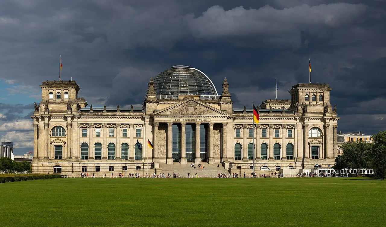 Fachada oeste do Reichstag, em Berlim, com a cúpula de vidro, sob céu carregado.