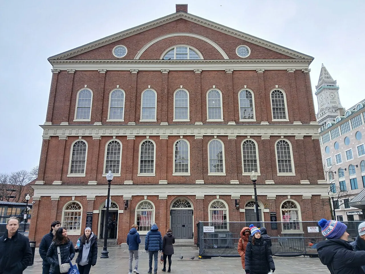 Faneuil Hall, em Boston, prédio de tijolo com torre do relógio e cata-vento dourado no topo.