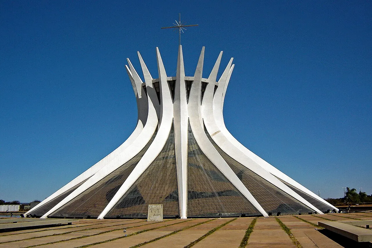 Catedral de Brasília, com as dezesseis colunas curvas de concreto e o vitral, sob céu azul.