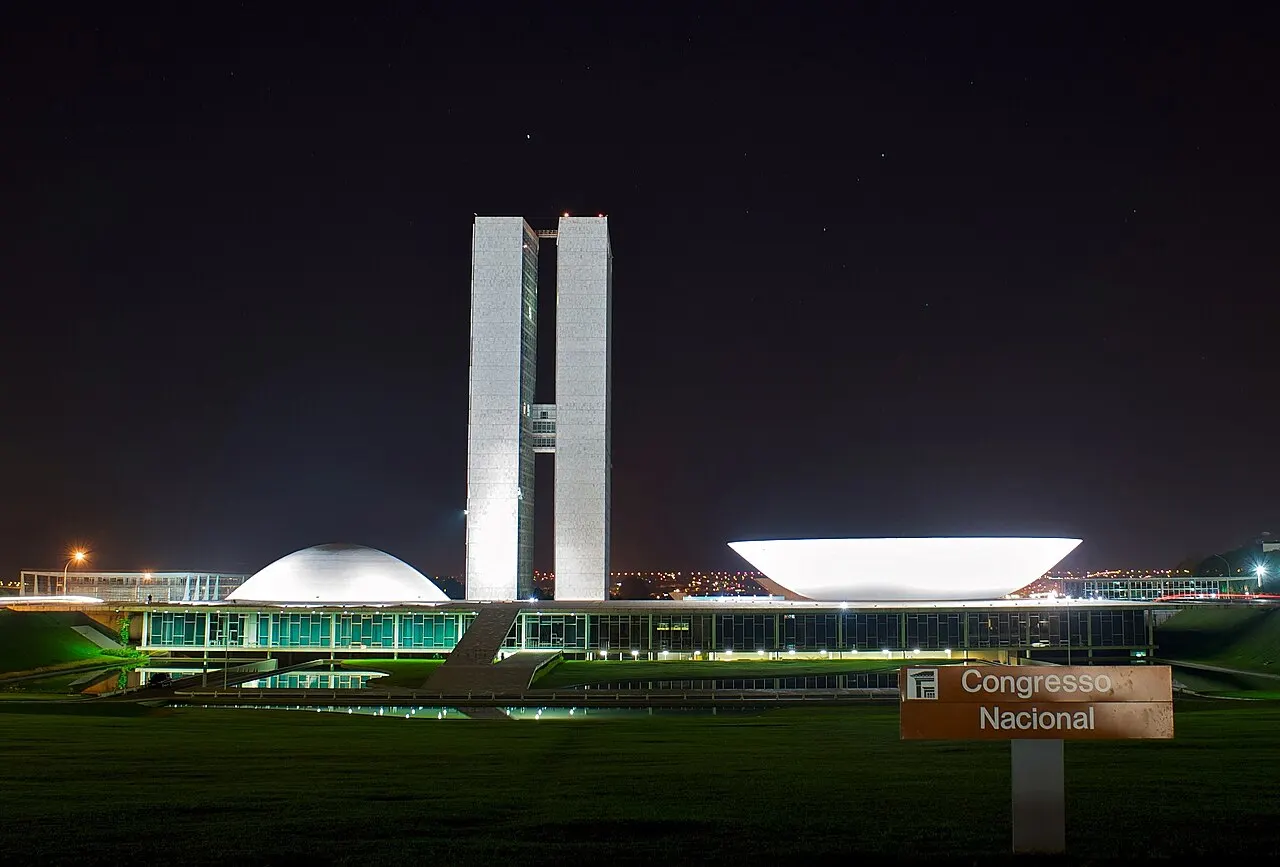Torres gêmeas do Congresso Nacional, em Brasília, com as cúpulas do plenário ao lado, iluminadas à noite.