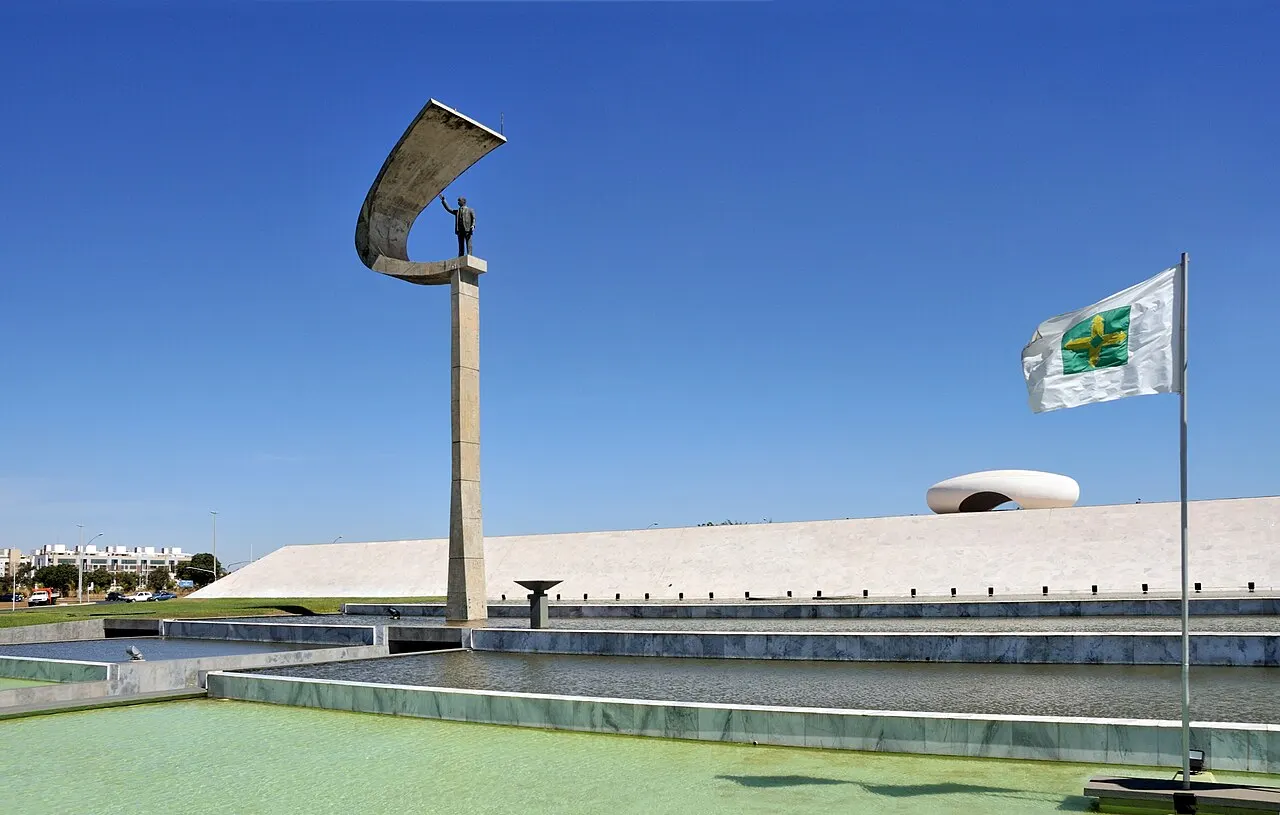 Estátua de Juscelino Kubitschek sob o arco curvo de concreto do Memorial JK, em Brasília.