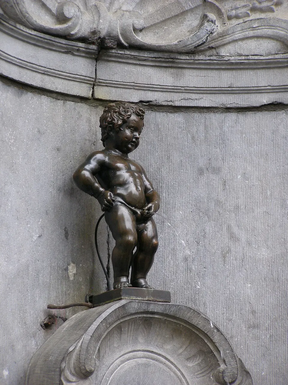 Estátua de bronze do Manneken Pis, em Bruxelas, no nicho de pedra da fonte.