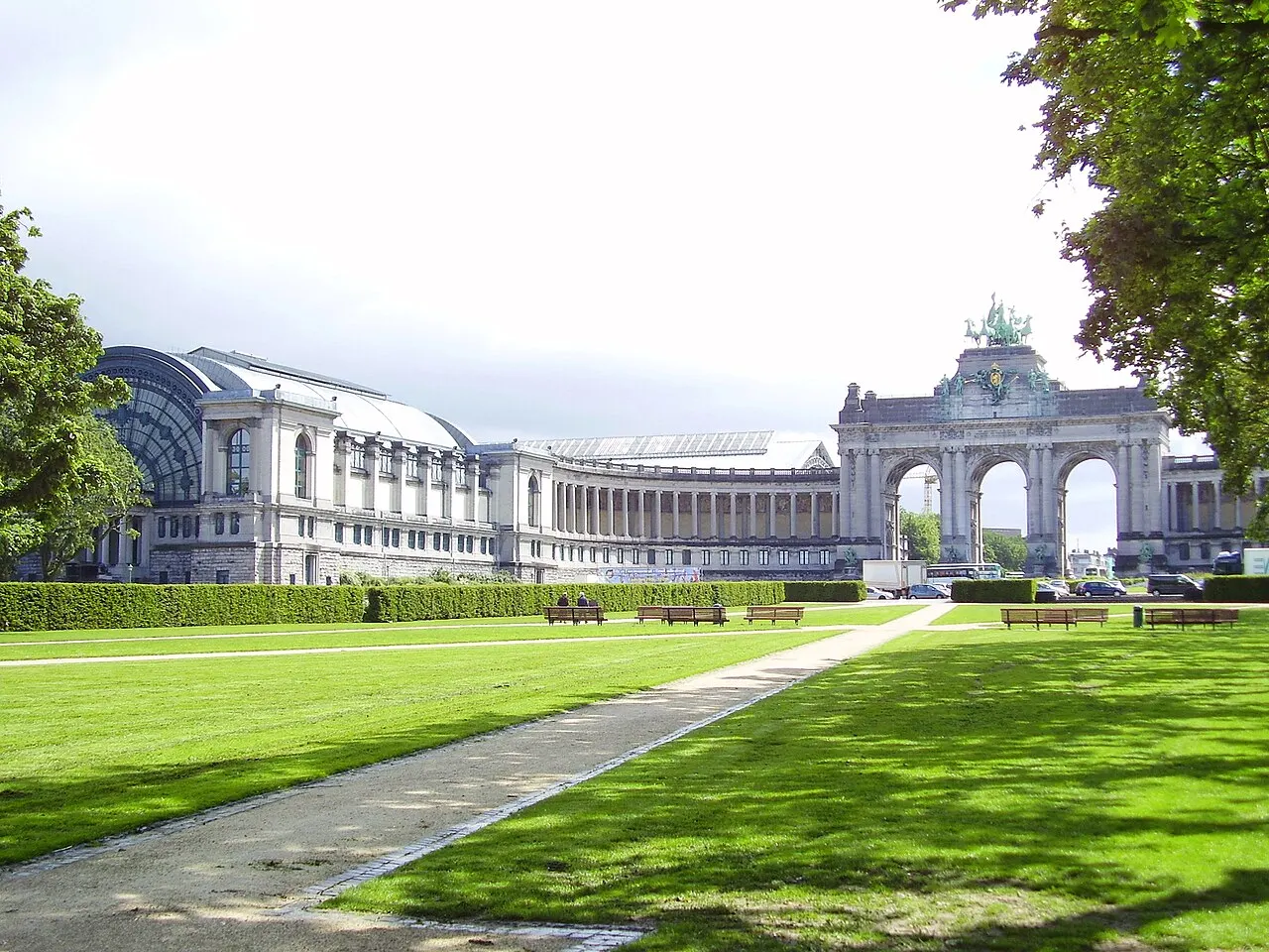 Arcada triunfal e pavilhões do Parc du Cinquantenaire, em Bruxelas, atrás de um gramado.