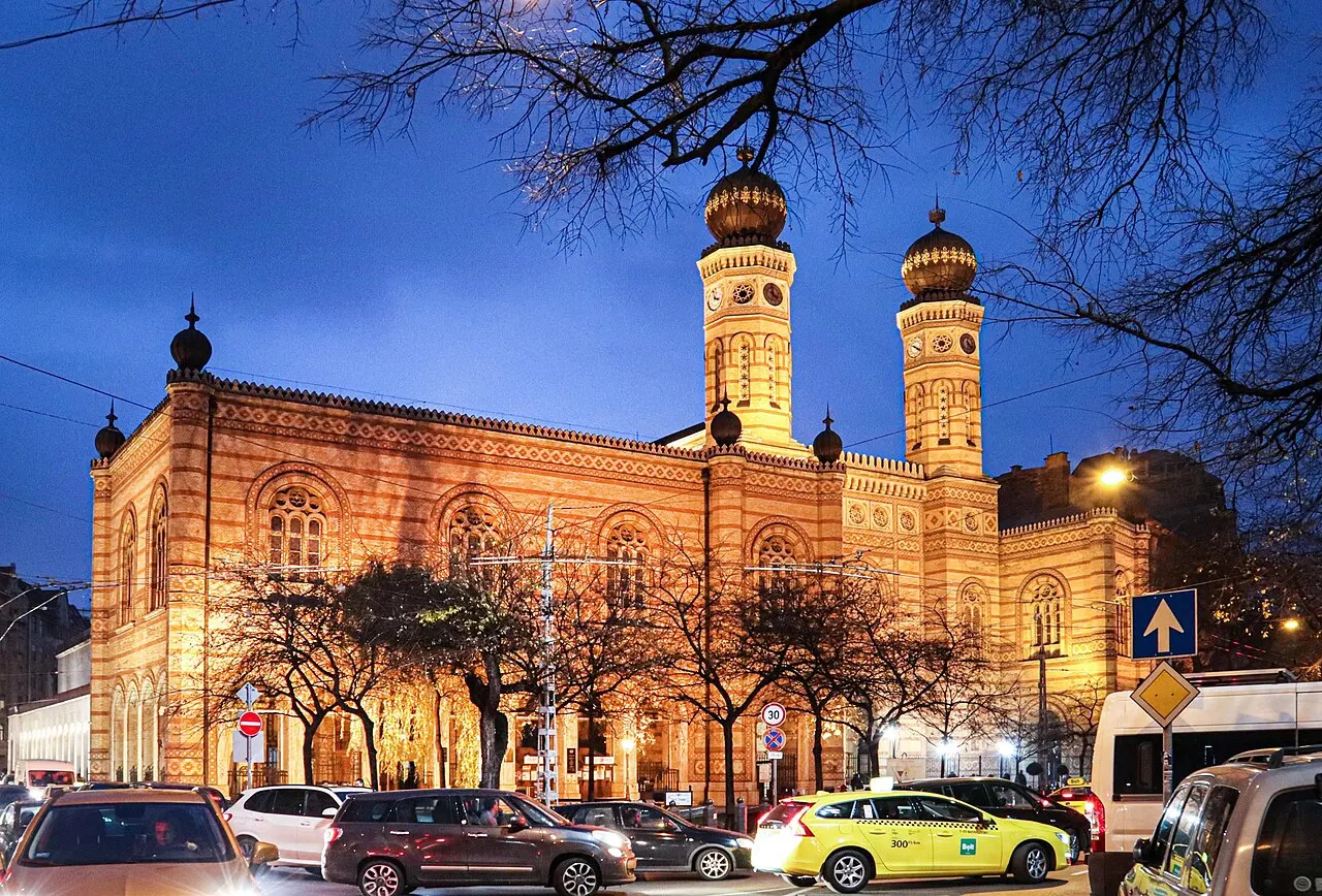 Sinagoga da Rua Dohány, em Budapeste, com as duas torres de cúpula, iluminada ao entardecer.