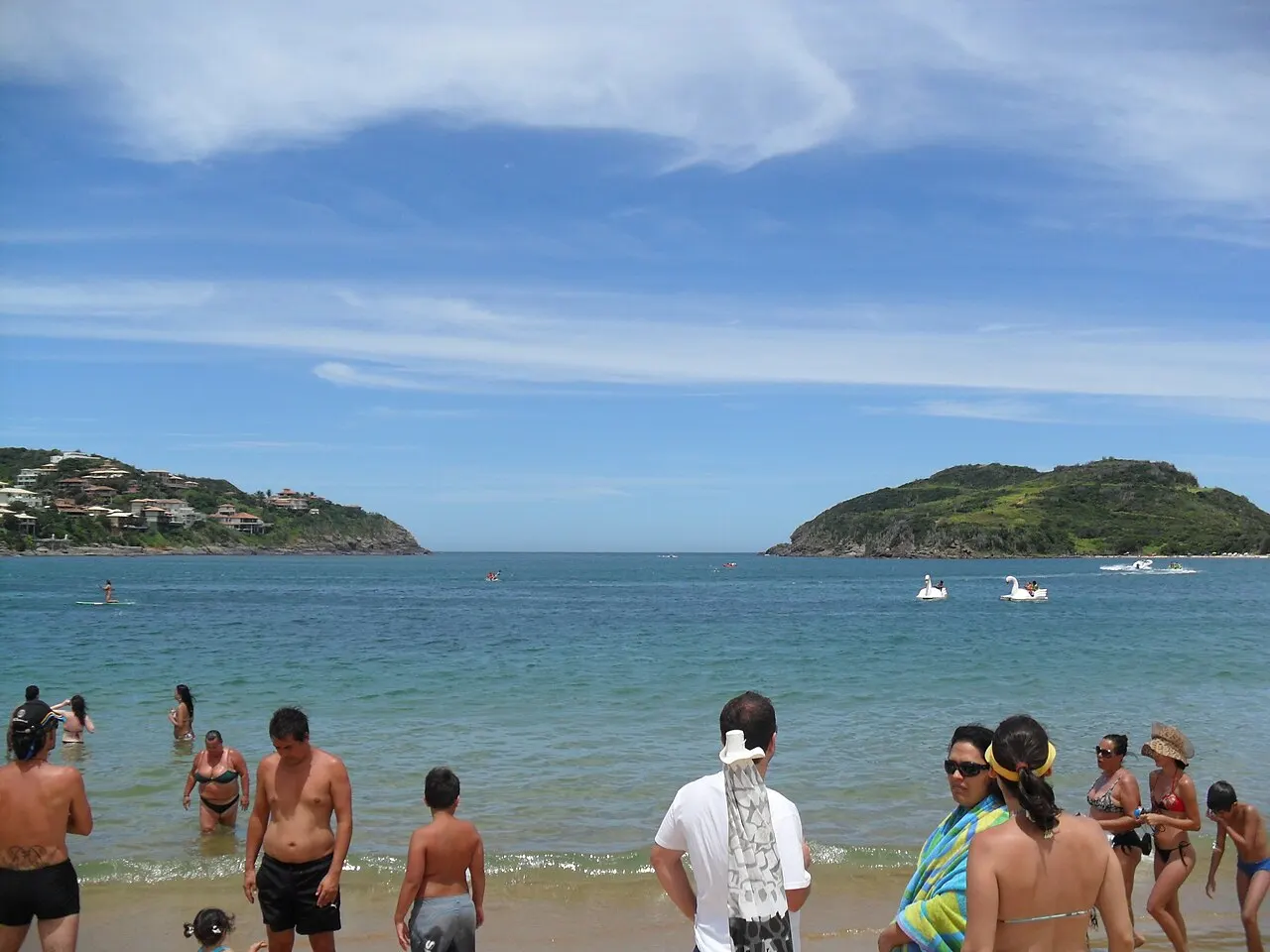 Swimmers in the calm water of Praia da Ferradura, with the headlands closing the cove behind.