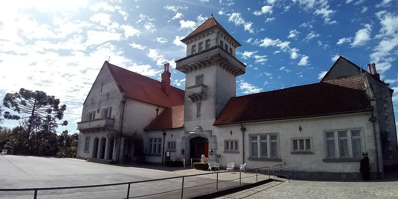 A fachada do Palácio Boa Vista, de paredes claras e telhado vermelho, com a torre ao centro, sob céu azul com nuvens.