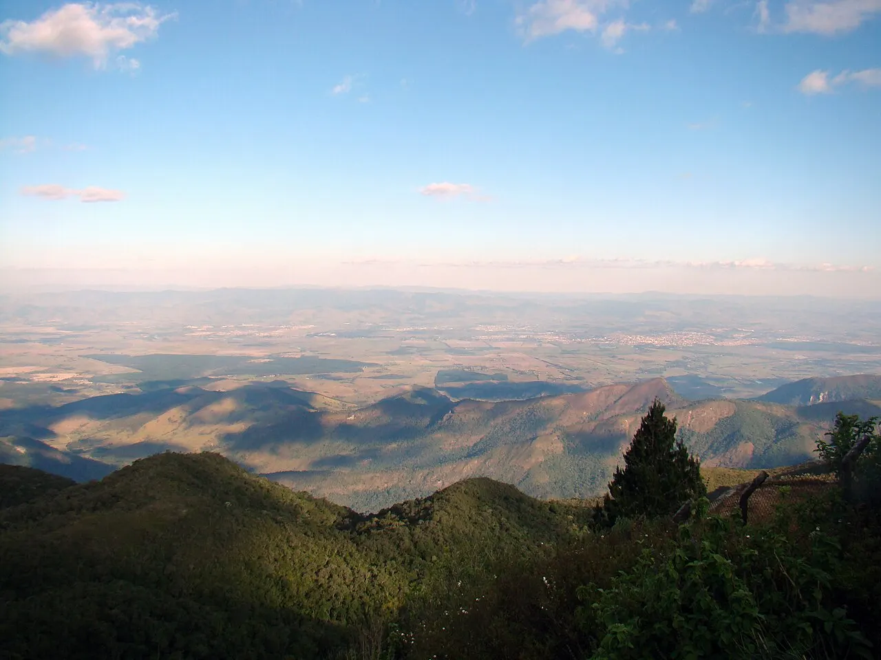 A vista do alto do Pico do Itapeva, com a serra coberta de mata em primeiro plano e o vale do Paraíba se abrindo até o horizonte.