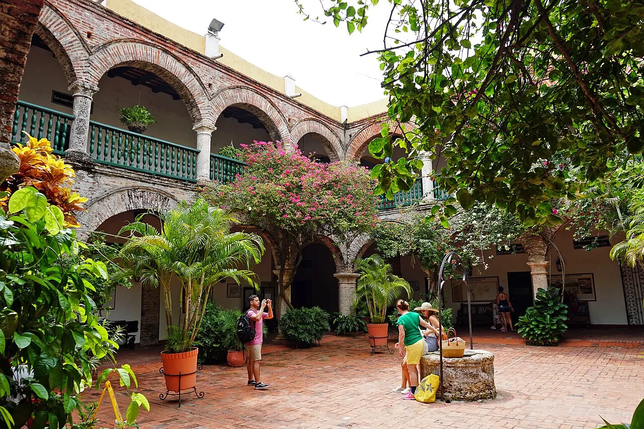 O pátio do Convento de Santa Cruz de la Popa tem arcos nos dois andares, plantas e piso de tijolo.