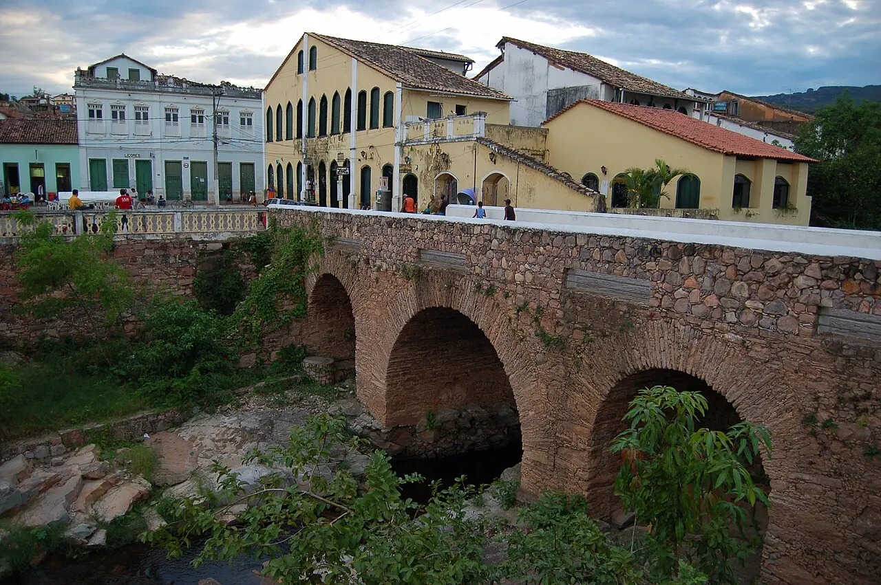 A ponte de pedra em arcos sobre o rio Lençóis, com o casario colonial amarelo e branco do centro logo atrás.