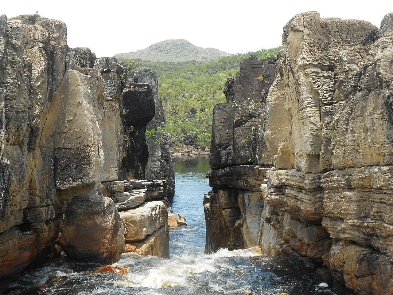 O rio passando por uma fenda estreita entre as paredes de pedra do Cânion II, com o morro ao fundo.