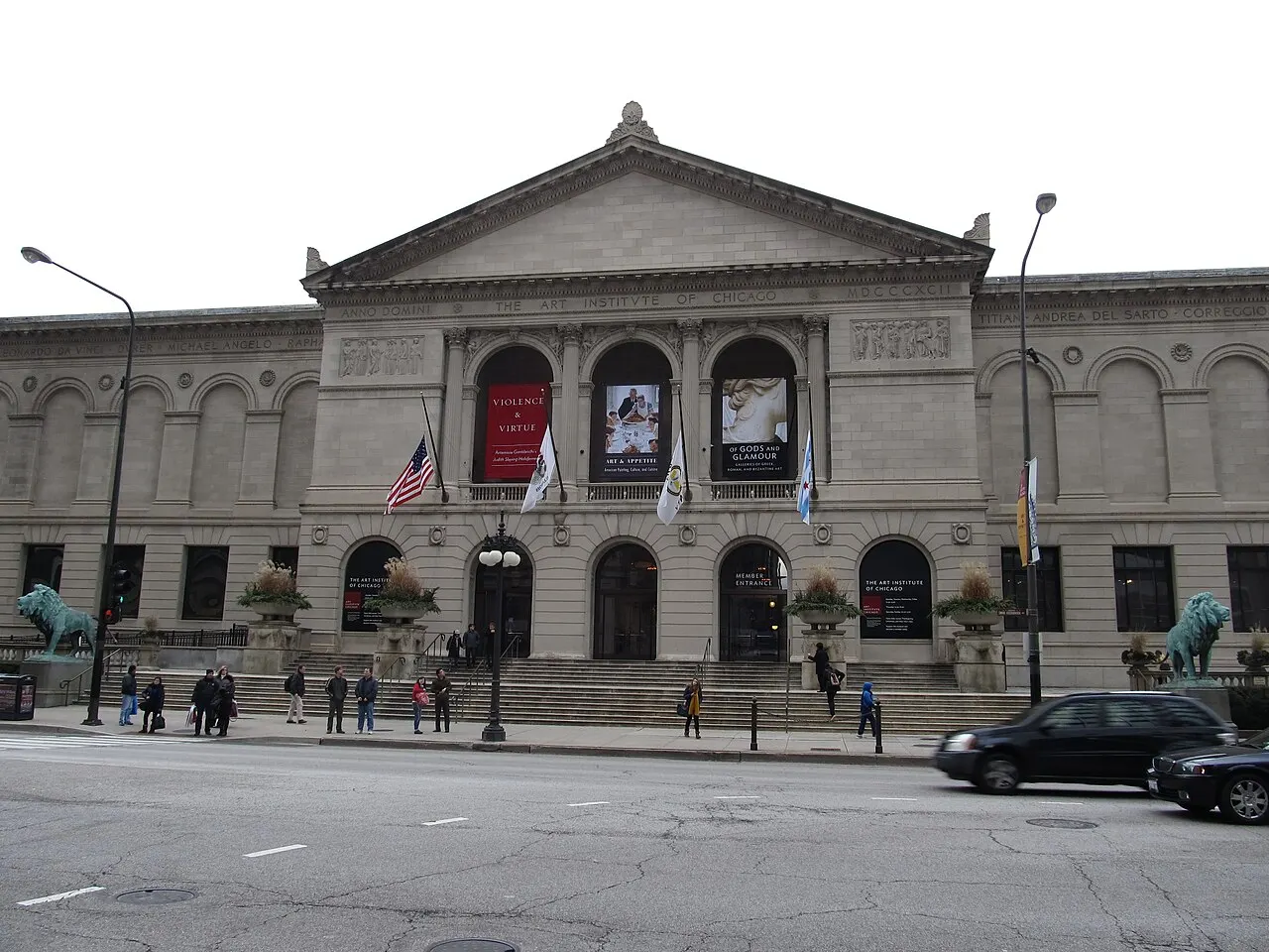 Fachada neoclássica de pedra clara do Art Institute of Chicago, com frontão, colunas e os dois leões de bronze na escadaria, vista da avenida.