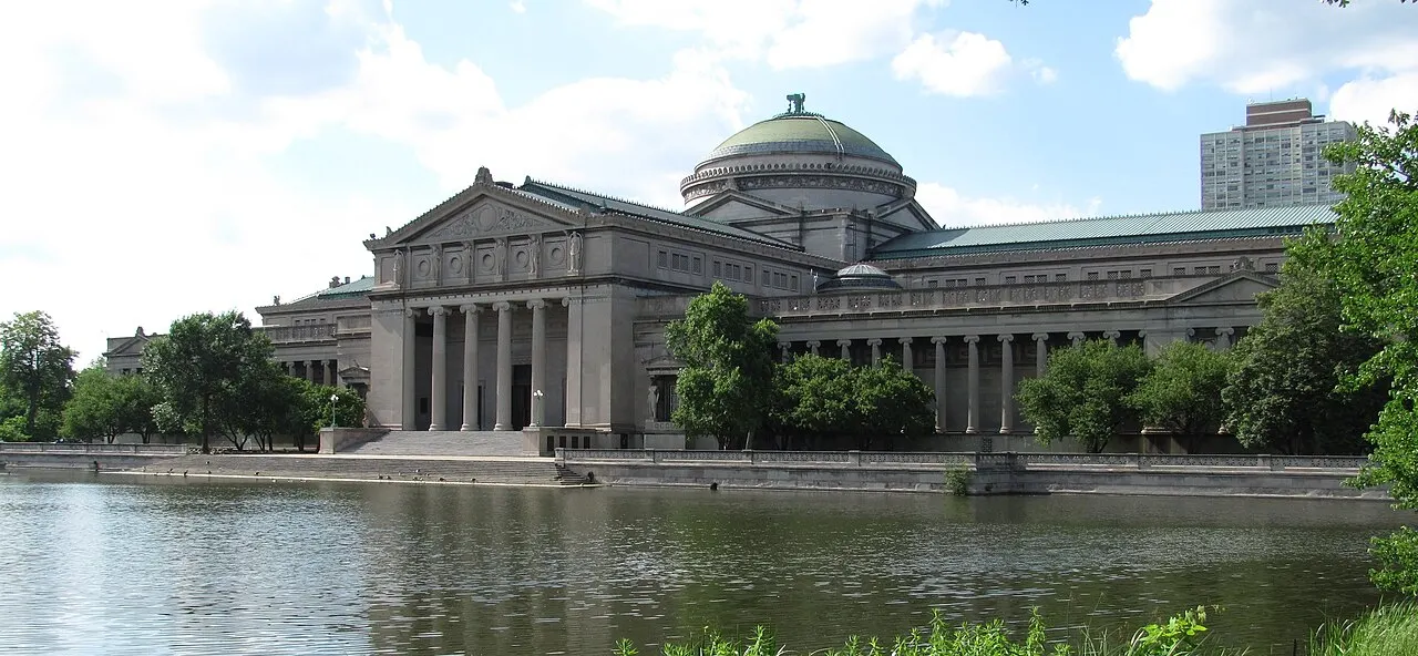 Museu de Ciência e Indústria de Chicago, prédio neoclássico com cúpula, visto do outro lado de um lago.