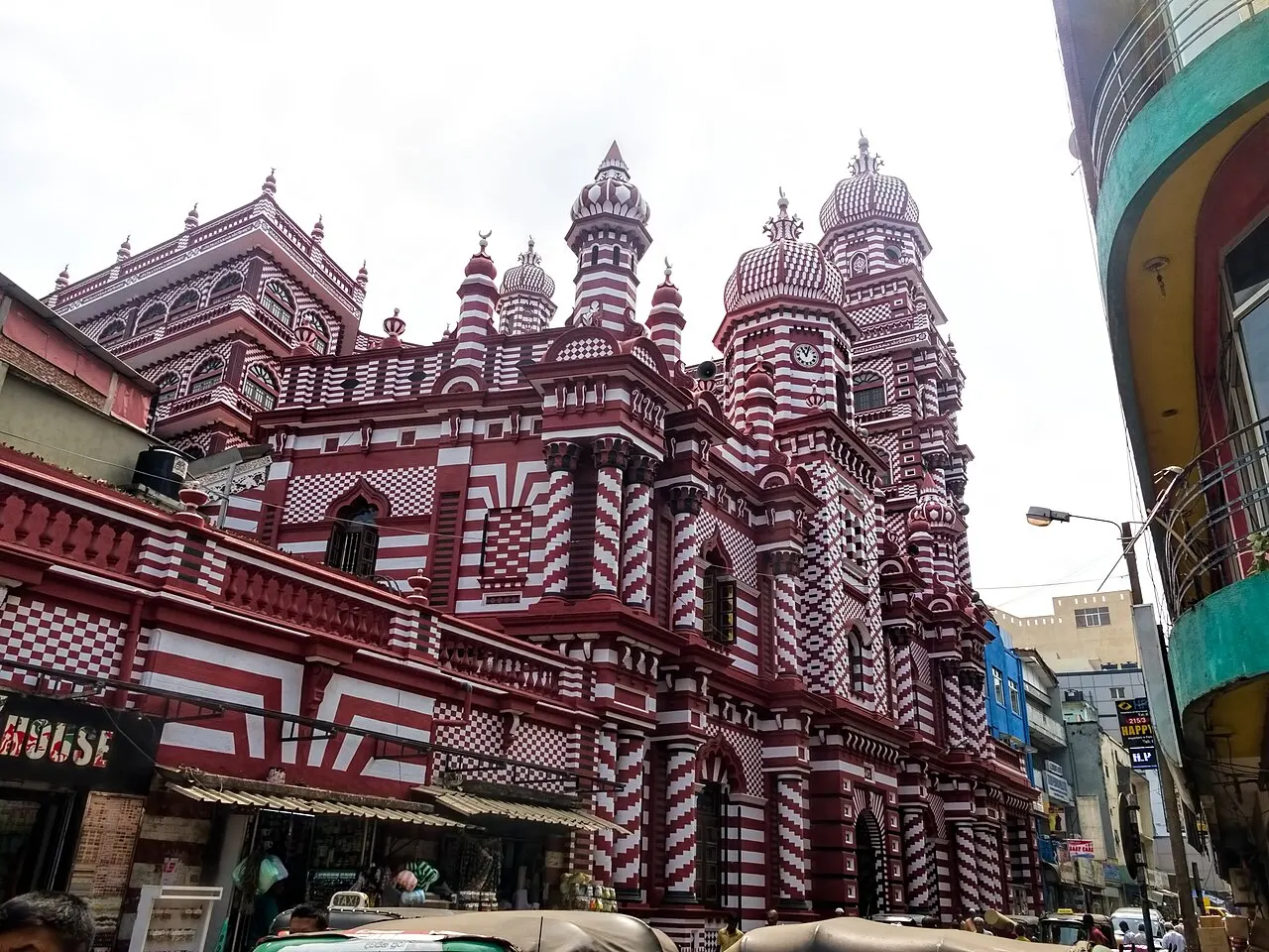 Mosquée à façade rayée rouge et blanc, tours et dômes pointus.