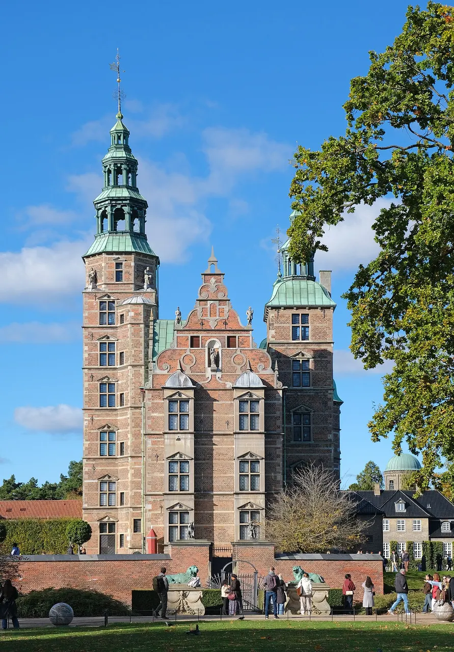 Castelo de Rosenborg, em Copenhague, de tijolo vermelho com torres e telhados verdes de cobre, sob céu azul.