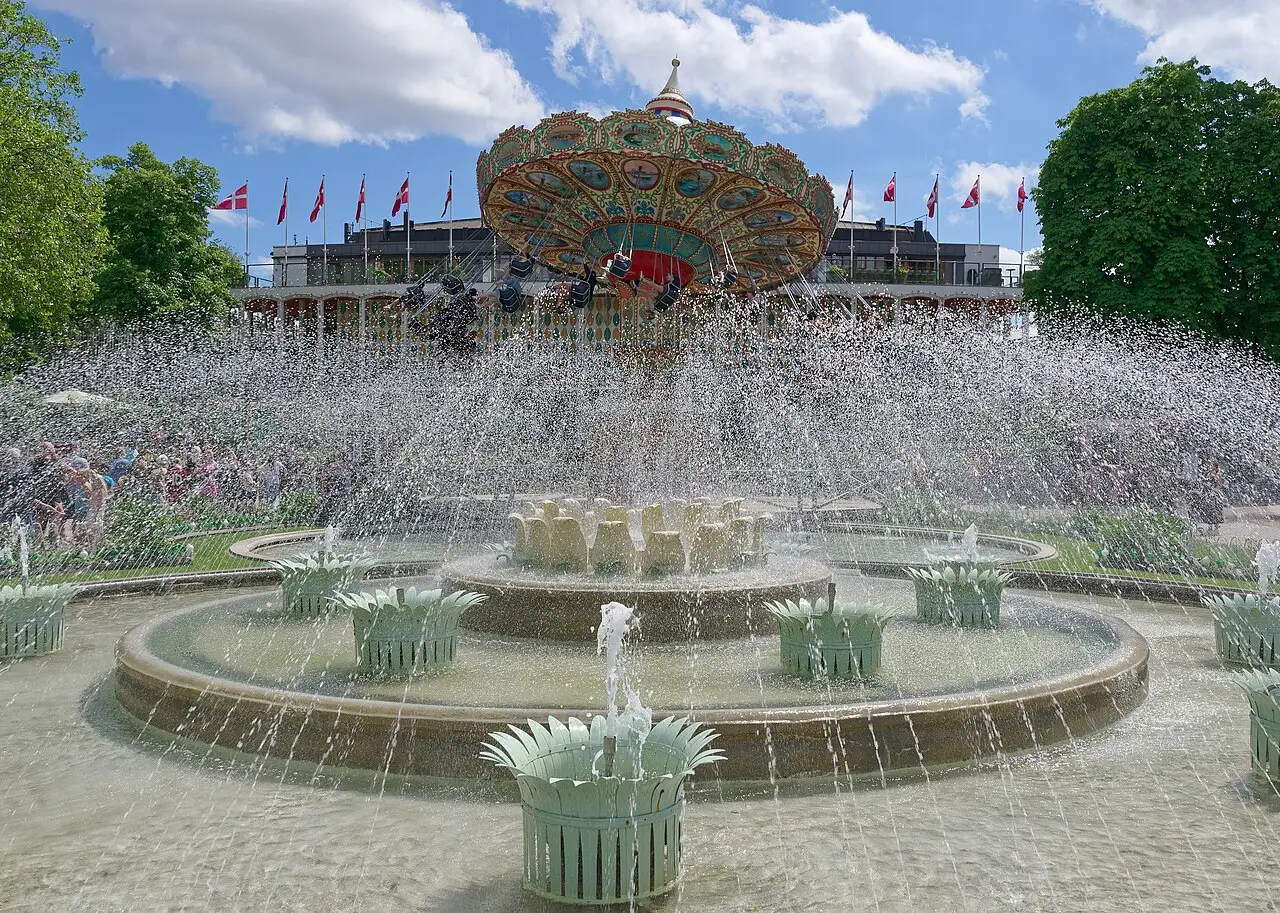 Fonte circular do Tivoli com muitos jatos e, ao fundo, um palco em leque colorido entre bandeiras.