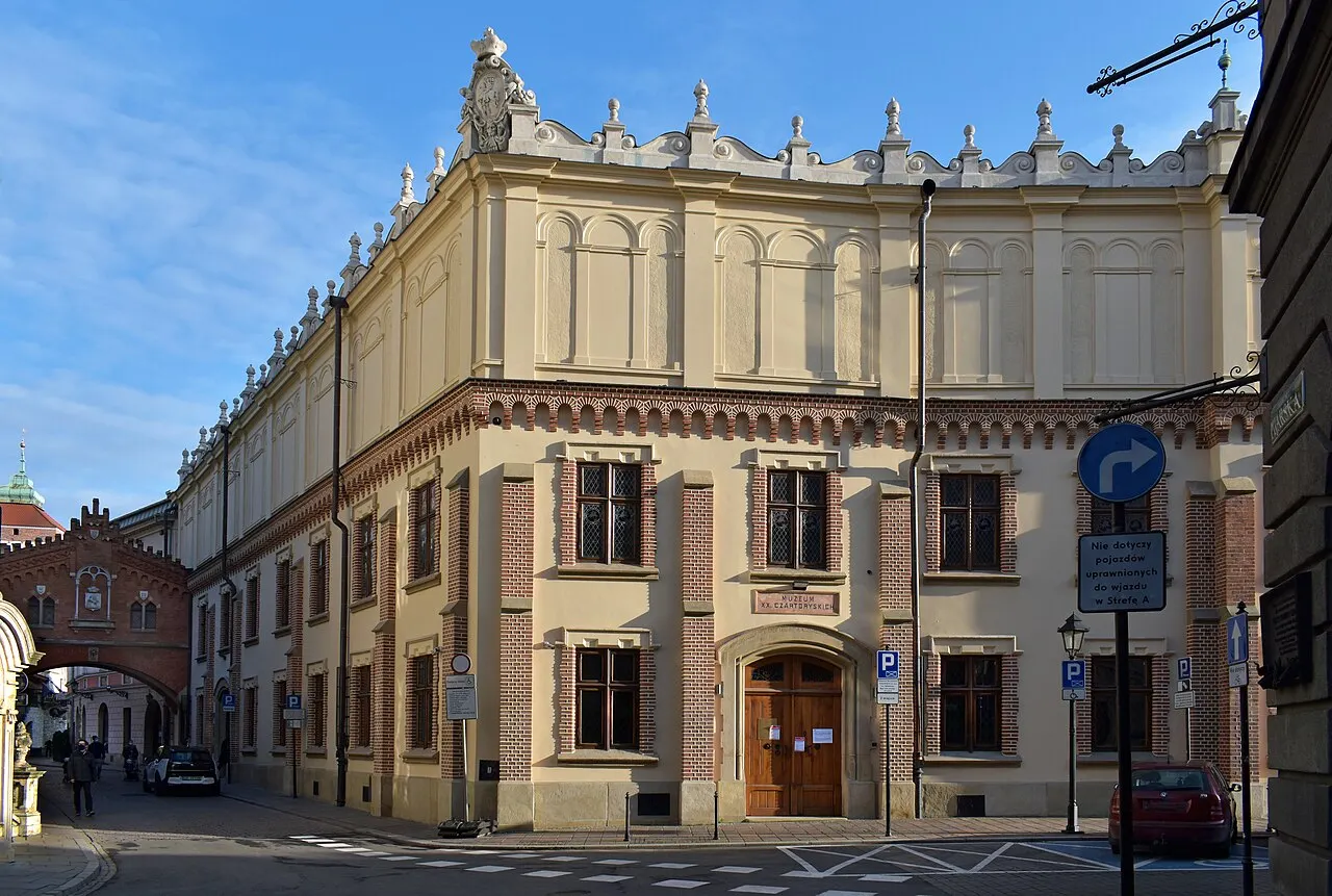 Palácio Czartoryski, em Cracóvia, prédio claro de esquina com passagem em arco sobre a rua.