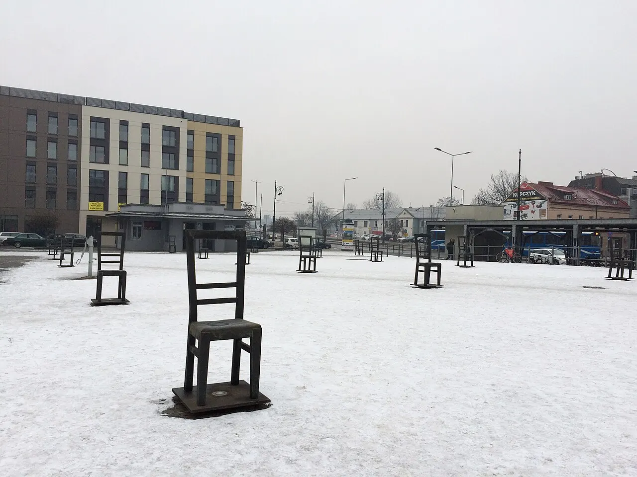 Cadeira de bronze do memorial da Praça dos Heróis do Gueto, em Cracóvia, na praça coberta de neve.