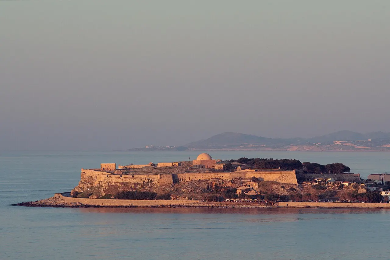 A Fortezza de Rethymno no promontório sobre o mar, com a cúpula da mesquita, na luz rosada do entardecer.