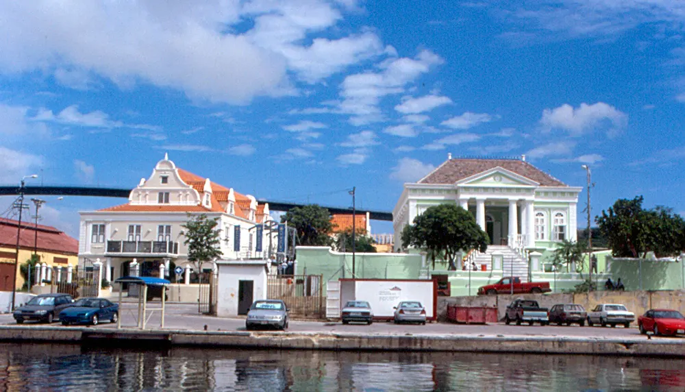 Os casarões coloniais de Scharloo, brancos e de telhado laranja, à beira do canal Waaigat, com carros estacionados na margem.