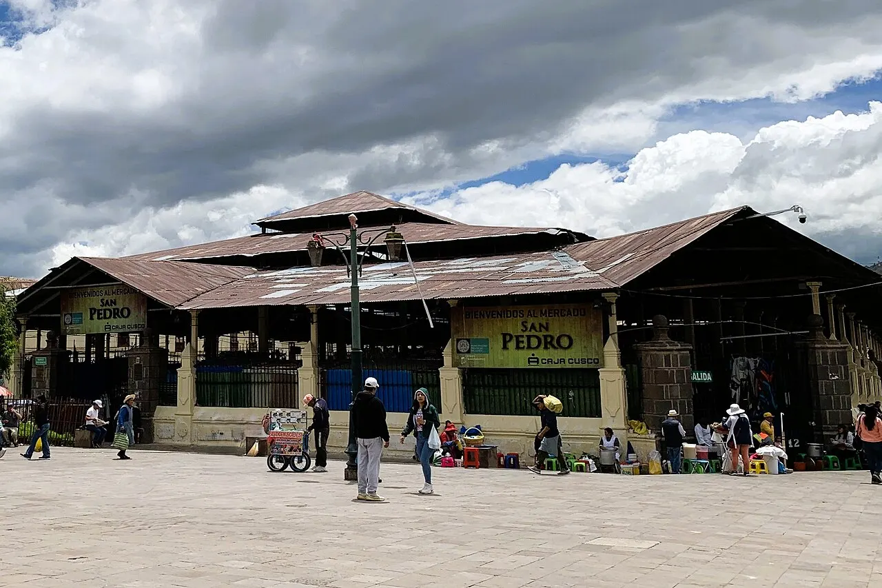 O Mercado de San Pedro, um galpão comprido de telhado metálico, abre para a praça com gente e bancas na frente.