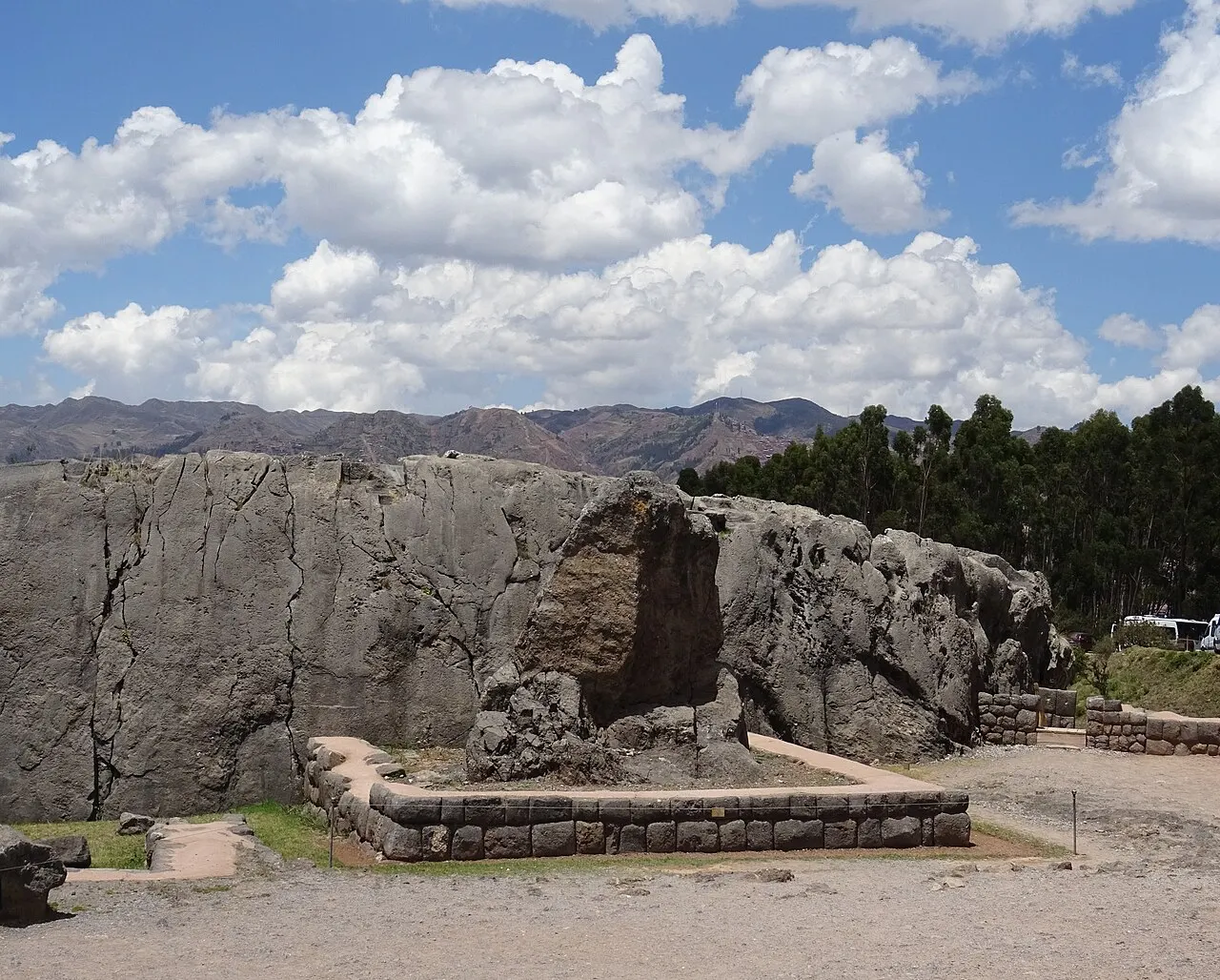 Monólito de pedra sobre uma plataforma de blocos no santuário inca de Q'enqo, perto de Cusco, diante de uma rocha grande.