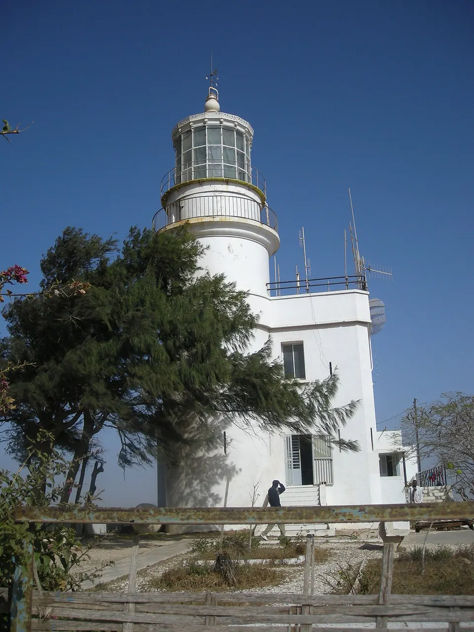 Farol das Mamelles, em Dakar, torre branca com galeria envidraçada, no alto do morro entre árvores.