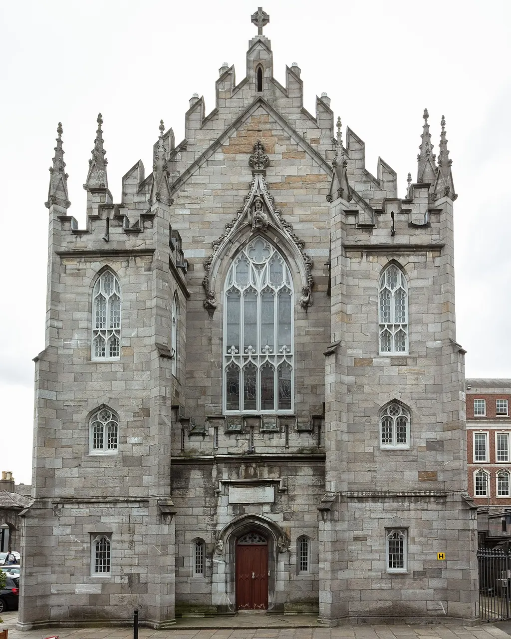 Fachada gótica de pedra de uma capela do Castelo de Dublin, com pináculos e uma grande janela.