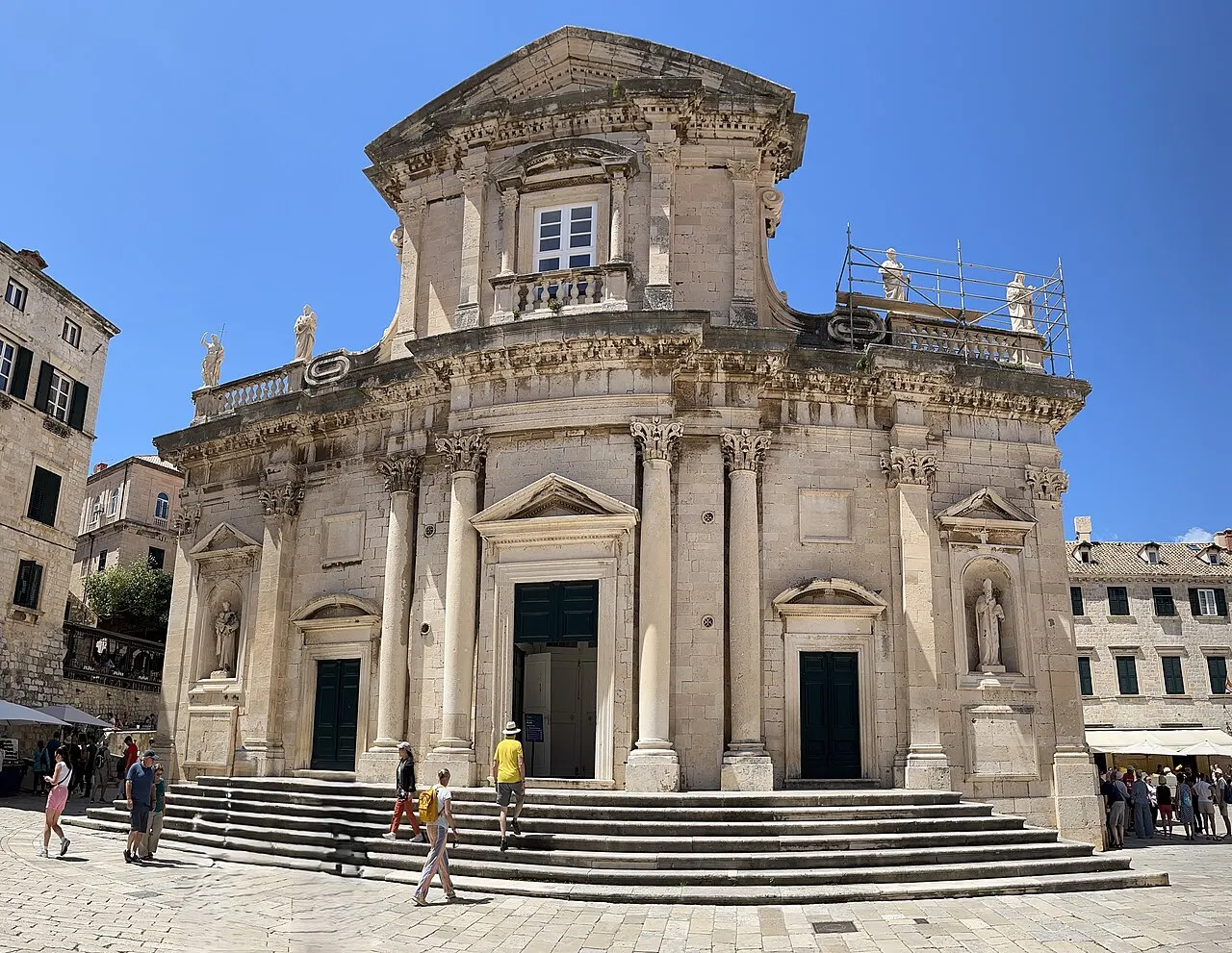 Fachada barroca da Catedral da Assunção, em Dubrovnik, de pedra clara, com a escadaria à frente.