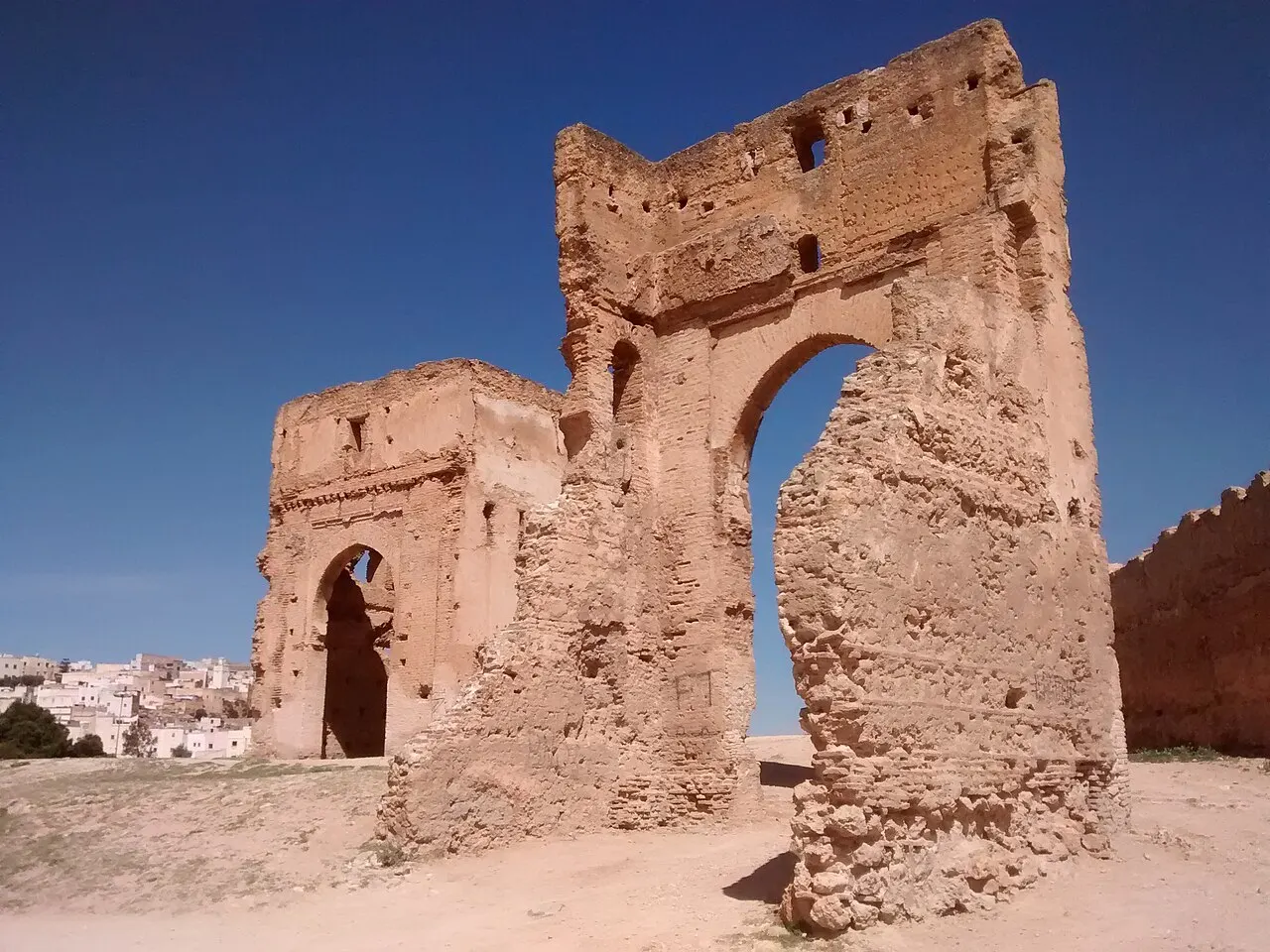 Ruínas de arco e paredes dos Túmulos merínidas, no alto da colina sobre Fez, sob céu azul.