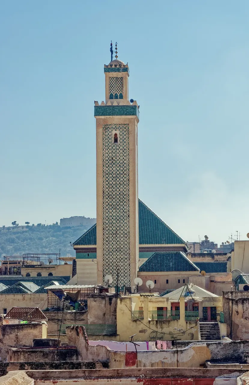 Minarete da Zaouia de Moulay Idriss II, em Fez, com faixa de azulejo verde, acima dos telhados da medina.