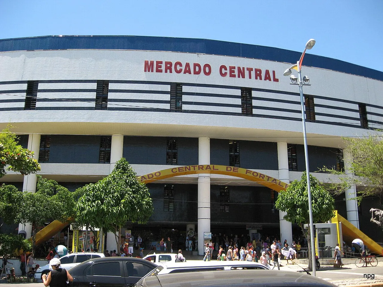 A fachada curva do Mercado Central de Fortaleza, com o letreiro vermelho no alto e gente entrando pela porta principal.