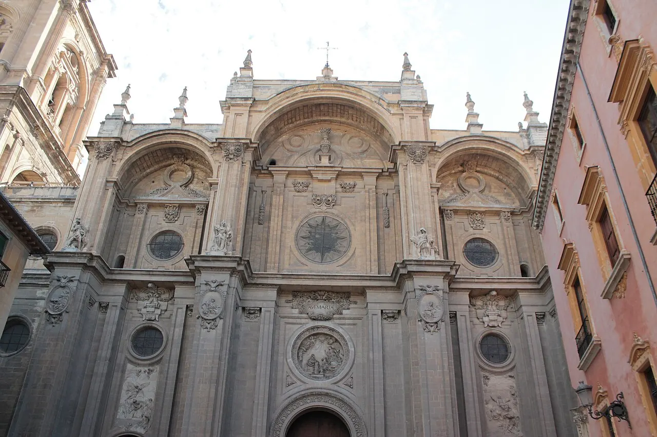 A fachada principal da Catedral de Granada, com três grandes arcos, medalhões de mármore e relevos, vista da Plaza de las Pasiegas.