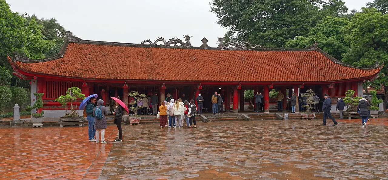 Pavilhão comprido de telhado vermelho curvo, sustentado por colunas, aberto nas laterais.