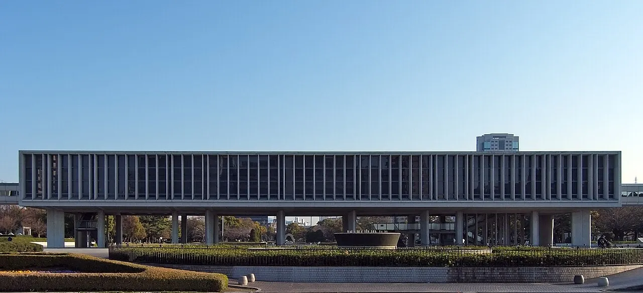Edifício horizontal de concreto sobre pilotis, com fachada de brise-soleil, sob céu azul.