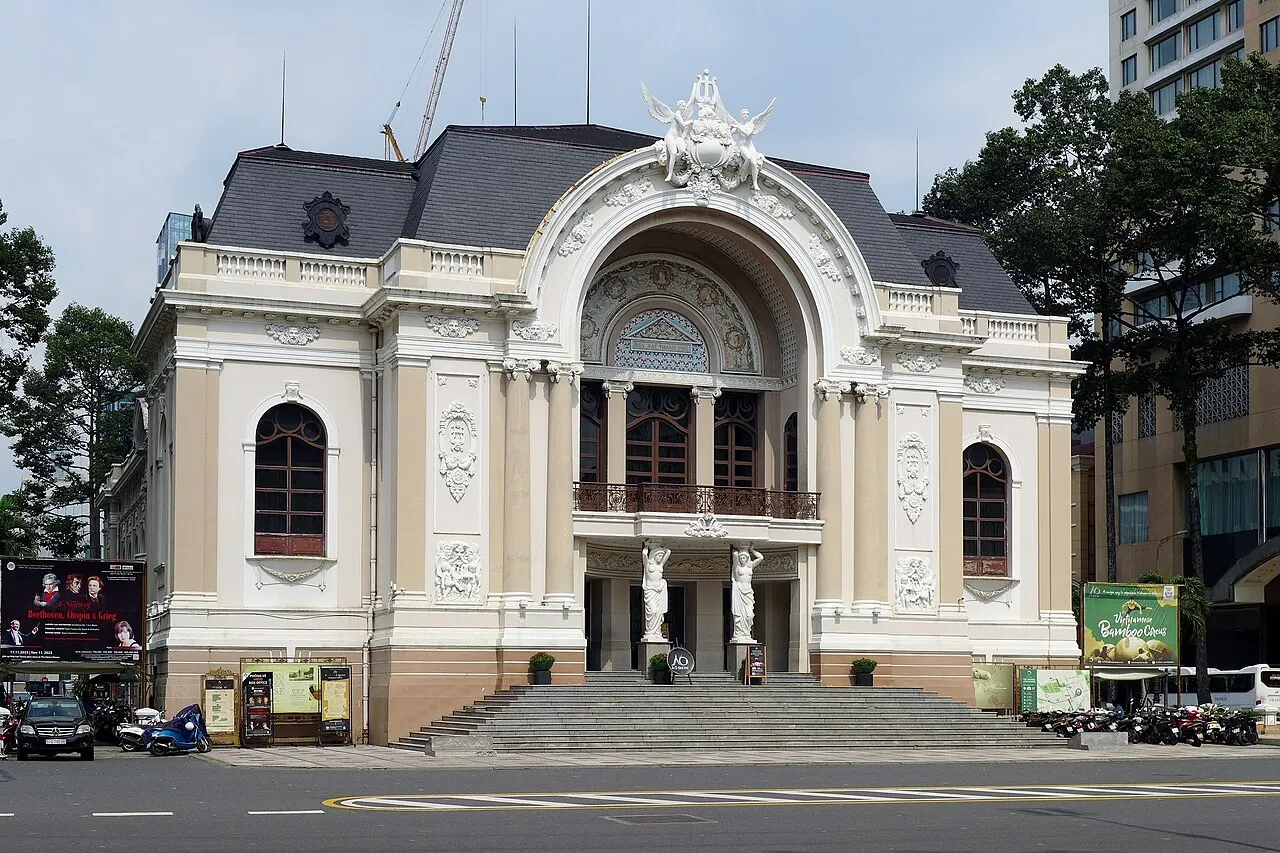 Teatro de estilo colonial francês, com colunas, estátuas e telhado de ardósia cinza.