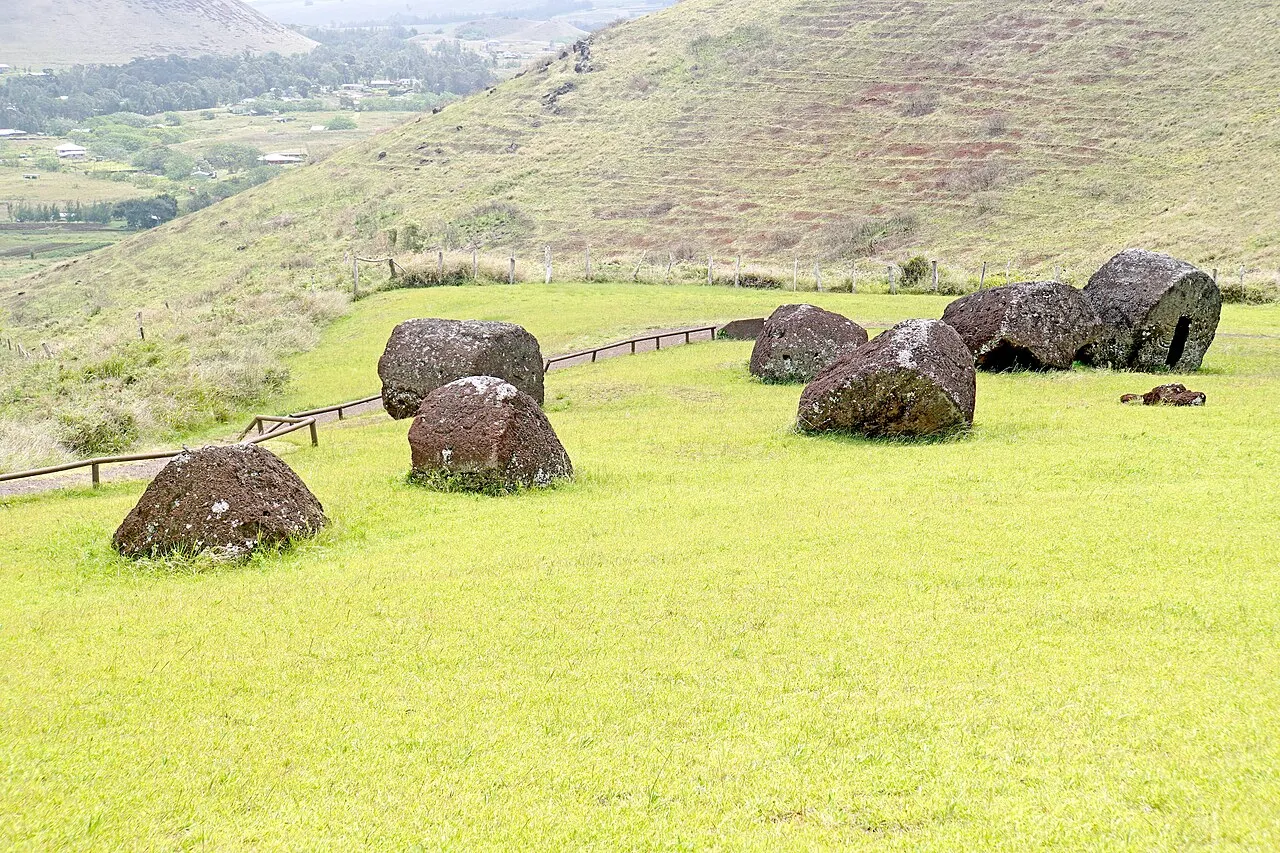 Cilindros de escória vermelha, os chapéus dos moais, espalhados pelo gramado ao pé da encosta de Puna Pau.
